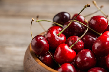 Ripe and juicy cherries in wooden bowl on the dark rustic background. Selective focus. Shallow depth of field.