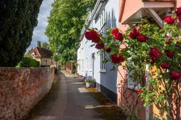 Fototapeta na wymiar English village path with rock wall and roses on the house wall