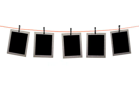 Blank Polaroid pictures hanging in a line on white background