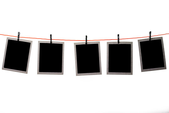Blank Polaroid pictures hanging in a line on white background