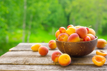 Fresh apricots in bowl on wooden table outdoor ,copy space