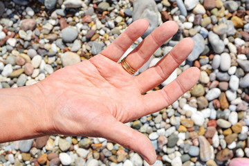 Men's tanned hands, make different compositions of fingers on the background of sea pebbles