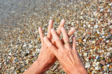 Men's tanned hands, make different compositions of fingers on the background of sea pebbles