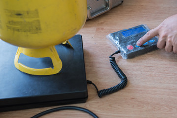 Refrigerant tank equipment for filling air conditioners on digital weight scale.