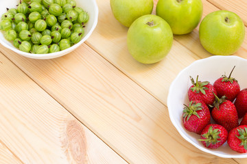 Fresh fruits and berries on a light wooden table with copy space
