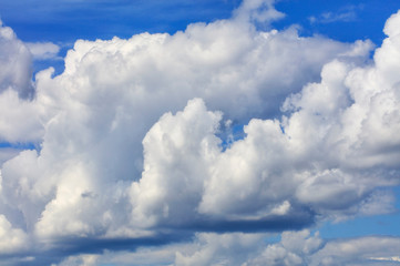 White-gray large clouds condenses into a rainy cloud in the blue sky, close-up.