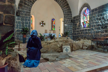 Tabgha, Israel - May 18 2019: Nun praying in the Church of the multiplication of the loaves and fishes in Tabgha, Israel