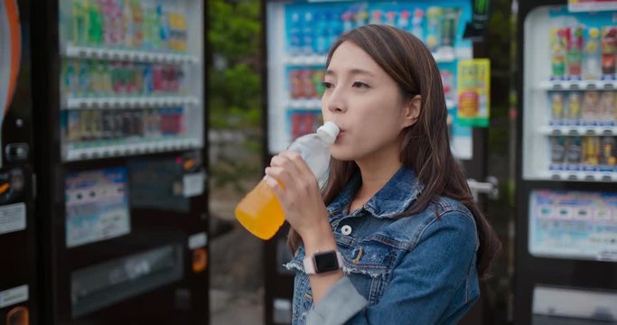 Woman drink of bottle of orange juice in vending machine