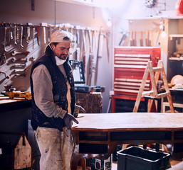 Male carpenter working on old wood in a retro vintage workshop.