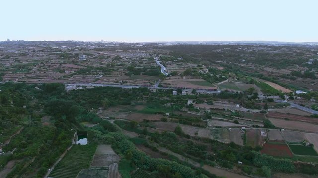 Aerial Maltese Landscape, road to Verdala Palace, buskette gardens, Siggiewi, Malta, drone dolly in establishing shot