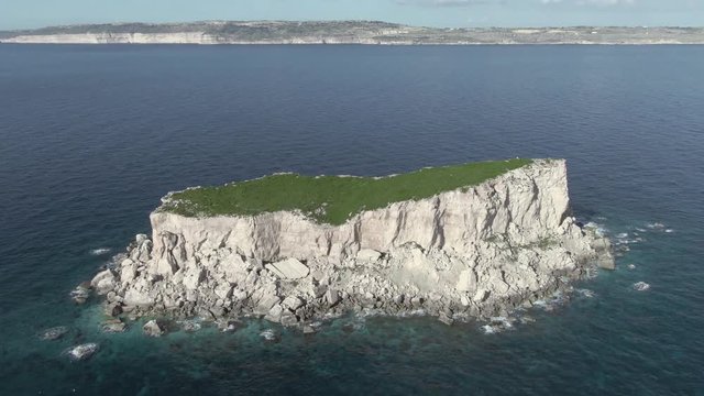 Static aerial view of the island of Filfla off of the coast of Malta with downward pan to reveal the whole island