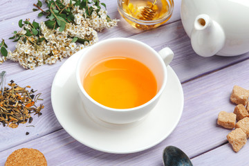Cup of tea with sugar cubes and flower branches on wooden table close up