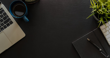Top view of black leather office desk with laptop, computer, office supplies and copy space