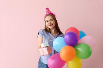 Happy woman with gifts and Birthday balloons on color background