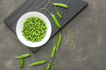 Bowl with tasty fresh peas on grey background