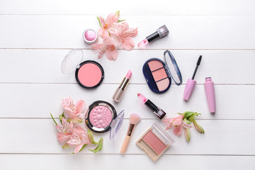Fototapeta na wymiar Set of makeup cosmetics with flowers on white wooden background