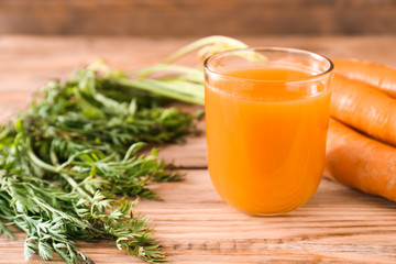 Glass of tasty carrot juice on wooden table