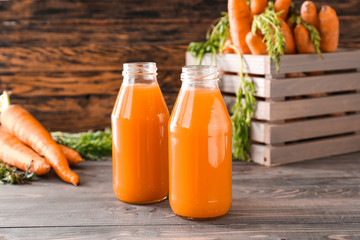 Bottles of tasty carrot juice on wooden table
