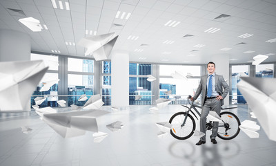 Smiling man in business suit standing with bike