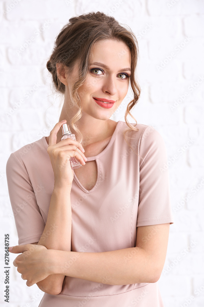 Wall mural beautiful young woman with bottle of perfume on white background