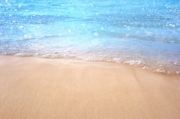 tropical sandy beach blurred background Sandy shore washing by the wave Bright turquoise ocean water .crystal clear sea and bokeh ,summer concept.