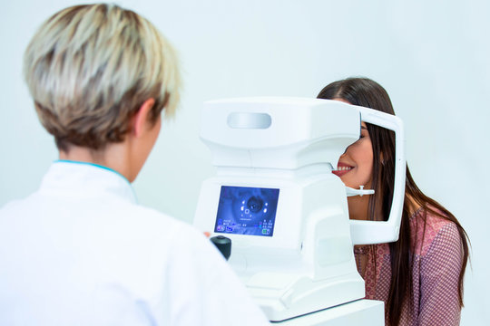 Female doctor ophthalmologist is checking the eye vision of attractive young woman in modern clinic. Doctor and patient in ophthalmology clinic.