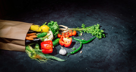 Healthy food in full paper bag of different products vegetables and fruits on dark background