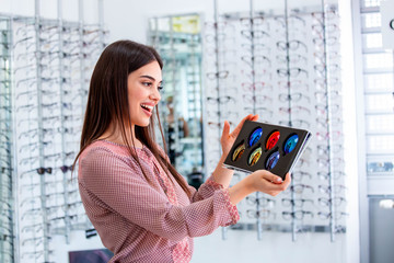 Attractive young female doctor in ophthalmology clinic showing different polarized lens
