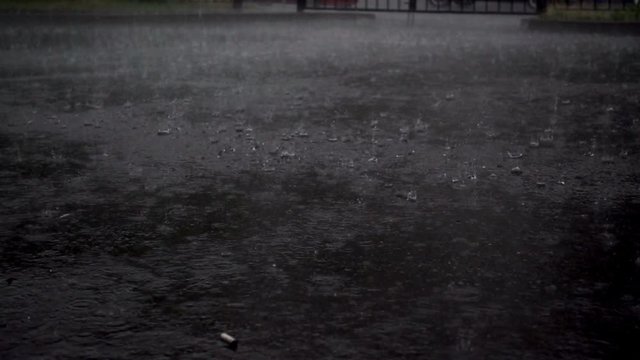 Slow motion raindrops fall into a large puddle as a background. Bad weather. Heavy rain.