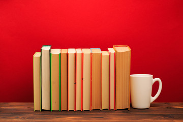  pile of old books with mug , panorma, good copy space  on red background