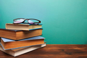  pile of old books with glasses panorma, good copy space  on blue background