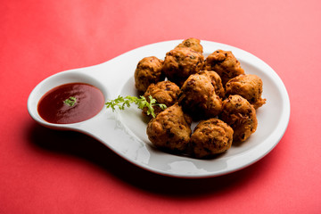 rava Bhajj or bhajiya also known as suji Pakoda or semolina Pakora, served with tomato ketchup. selective focus