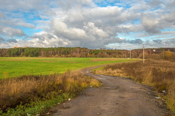 Country road rut with puddles through agricultural field