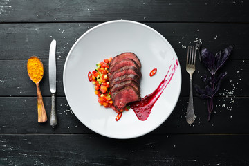 Veal baked with vegetables. In the plate. Top view. Free space for your text.