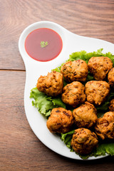 rava Bhajj or bhajiya also known as suji Pakoda or semolina Pakora, served with tomato ketchup. selective focus