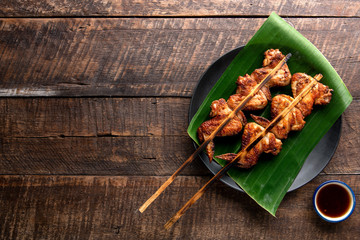 Grilled chicken Thailand style over banana leaf on wooden table background. Top view