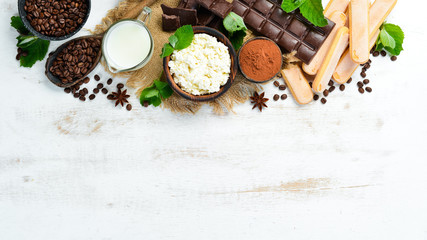 Ingredients for dessert tiramisu on a white wooden background.