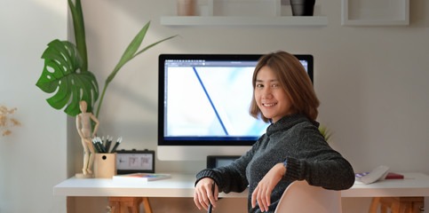 Fototapeta na wymiar Confident Asian female freelancer at her workspace desk