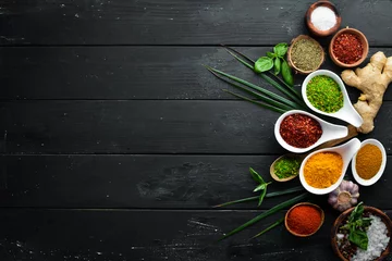  Large spice and herb collection in bowls and spoons. Indian spices. On a black wooden background. Top view. © Yaruniv-Studio