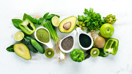 Fresh green vegetables in a rustic white background. Avocado, kiwi, onion, lime, parsley. Organic food. Rustic style. Top view. Free space for text.