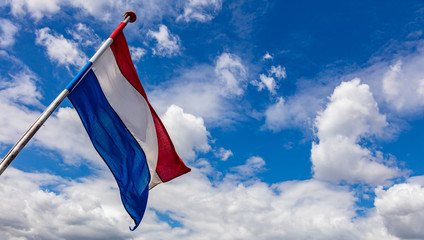 Holland flag waving against blue sky with clouds