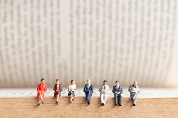 Miniature people : Businessman sitting on old book