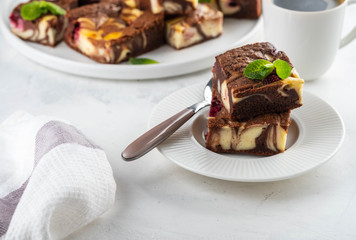 Cheesecake brownies with raspberry stacked on a white plate.