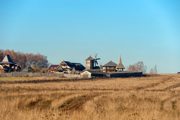 Fototapeta premium Autumn landscape. The road through the field to the entrance gate and the wooden wall of the Slavic Kremlin