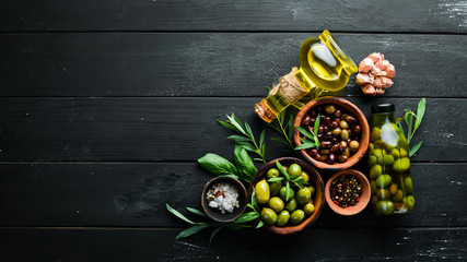 Olive oil and olives on a black wooden background.