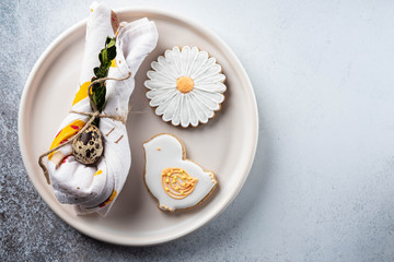 Table setting for the holiday of Easter. The photo shows white dishes, serving mat, Easter egg in a napkin. Napkin draped under rabbit ears.