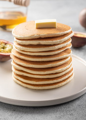 Fototapeta na wymiar Pancakes stack with butter and honey. Grey backround.
