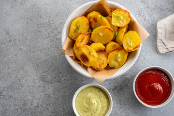 Baked potato wedges with cheese and herbs and tomato sauce on grey background - homemade organic vegetable vegan vegetarian potato wedges snack food meal.