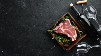Fototapeta na wymiar Raw T-bone steak on a black stone table. Top view. Free space for text.