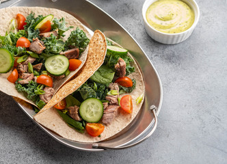 Two mexican pork carnitas tacos with sauces and vegetables.